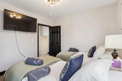 two beds in a room with a tv on the wall at Fairfax Urban Oasis - New Reno - 5 mins to Clinic in Cleveland