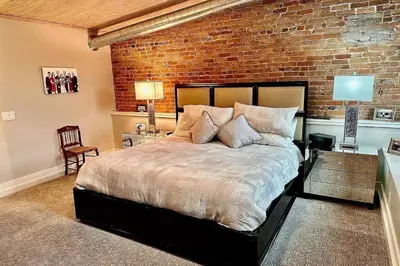 a bedroom with a large bed and a brick wall at Downtown Delight with Patio! 1 Mi to Ball State in Muncie
