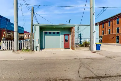 a building with a red door on a street at Downtown Delight with Patio! 1 Mi to Ball State in Muncie