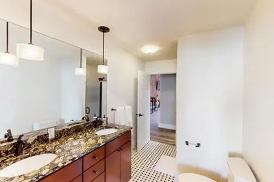 a bathroom with two sinks and a large mirror at Downtown Delight with Patio! 1 Mi to Ball State in Muncie