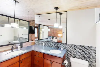 a bathroom with two sinks and a large mirror at Downtown Delight with Patio! 1 Mi to Ball State in Muncie