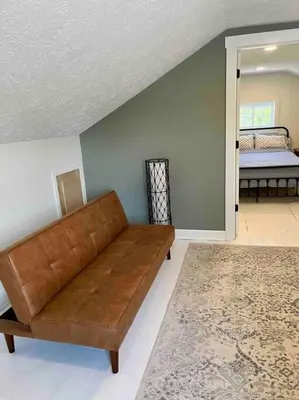 a living room with a brown couch and a bed at A Winfield Bungalow in Dover