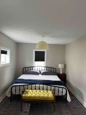 a bedroom with a large bed with a yellow bench at A Winfield Bungalow in Dover