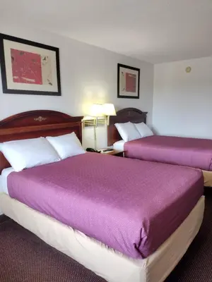 two beds in a hotel room with purple blankets at Hoosier Inn- Portland in Portland