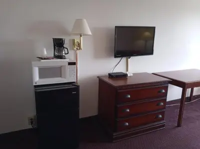 a hotel room with a microwave and a dresser with a tv at Hoosier Inn- Portland in Portland