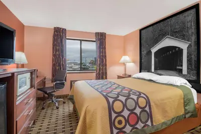 a hotel room with a bed and a desk and a television at Super 8 by Wyndham Shelbyville in Shelbyville