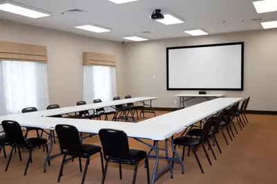a conference room with tables and chairs and a screen at Sleep Inn & Suites Belmont - St. Clairsville in Belmont