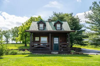 a log cabin with a green door in the grass at Sage Brush Cabin in Millersburg