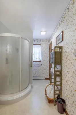 a bathroom with a walk in shower next to a wall at Sunset Cottage in Good Hope