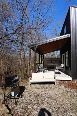 a black house with a white bed and a grill at Nature's Nest - Woodsy Retreat w/ Renovated Deck & Hot Tub in Logan