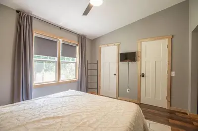 a bedroom with a large bed and a window at Nature's Nest - Woodsy Retreat w/ Renovated Deck & Hot Tub in Logan