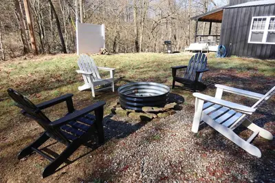 three chairs and a fire pit in a yard at Nature's Nest - Woodsy Retreat w/ Renovated Deck & Hot Tub in Logan