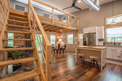 a kitchen and living room with a staircase in a house at Nature's Nest - Woodsy Retreat w/ Renovated Deck & Hot Tub in Logan