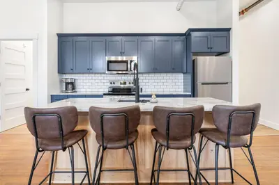 a kitchen with blue cabinets and a counter with stools at American Hall in Millersburg