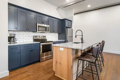 a kitchen with blue cabinets and a counter with stools at American Hall in Millersburg