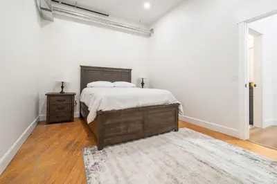 a white bedroom with a bed and a dresser and a rug at Young Suite in Millersburg