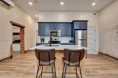 a kitchen with blue cabinets and a kitchen island with chairs at Kaufman Suite- BY BUSY INTERSECTION in Millersburg