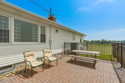 a patio with two chairs and a bench next to a house at Quiet Greenwich Home with Pool and Screened Porch! in Greenwich