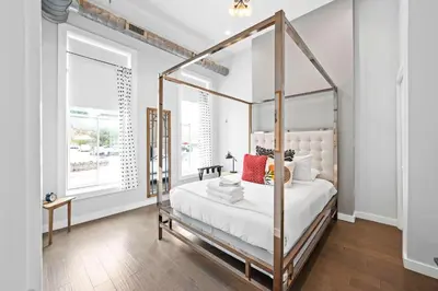 a bedroom with a canopy bed with white sheets and red pillows at 1BR with Parking - Walk to Convention Center & Stadiums in Covington