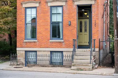 a brick house with a green door and stairs at 1BR with Parking - Walk to Convention Center & Stadiums in Covington