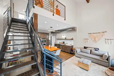 a living room with a staircase leading up to a kitchen at Downtown Views - Walk to Stadiums & Convention Center in Covington