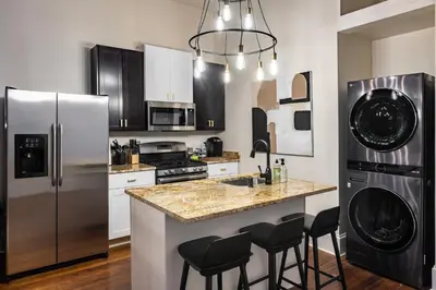 a kitchen with a refrigerator and a counter with stools at Walk to Downtown, Bars, Stadiums - Perfect for 4! in Covington