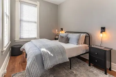 a bedroom with a bed and a table with a lamp at Main Street 2BR, Walk to Bars, Stadiums, Downtown in Covington