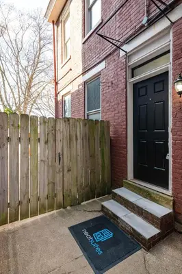 a house with a black door and a wooden fence at Main Street 2BR, Walk to Bars, Stadiums, Downtown in Covington