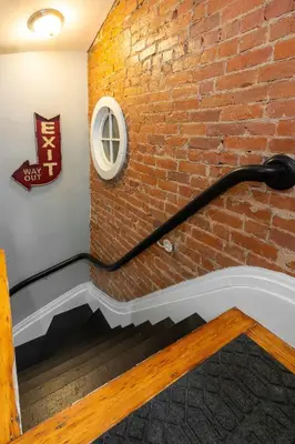 a brick wall with a black and white staircase at Main Street 2BR, Walk to Bars, Stadiums, Downtown in Covington