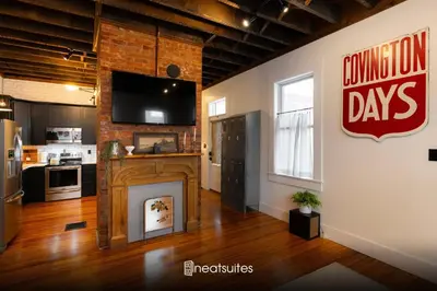a living room with a fireplace and a television on a wall at 1BR Downtown, Close to Cincinnati Stadiums & Bars in Covington
