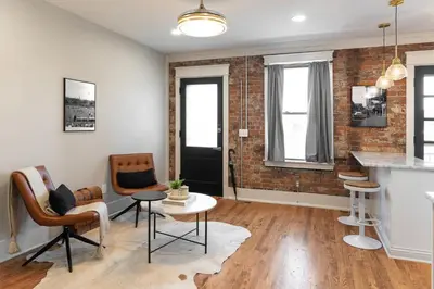 a living room with a brick wall and a table and chairs at 2BR Townhome with Parking - Walk to Stadiums & Downtown in Covington