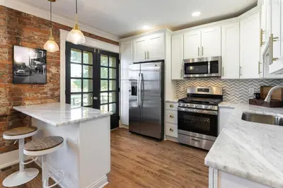 a kitchen with white cabinets and stainless steel appliances at 2BR Townhome with Parking - Walk to Stadiums & Downtown in Covington