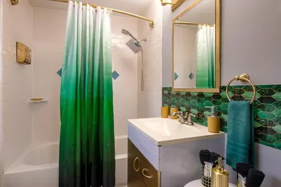a bathroom with a green shower curtain and a sink at The Tremont Emerald - By Christmas Story House - Historic Charm & Modern Comfort Near Downtown With Parking, 300MB Wifi & Self Check-In in Cleveland