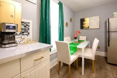 a kitchen with a table with chairs and a refrigerator at The Tremont Emerald - By Christmas Story House - Historic Charm & Modern Comfort Near Downtown With Parking, 300MB Wifi & Self Check-In in Cleveland