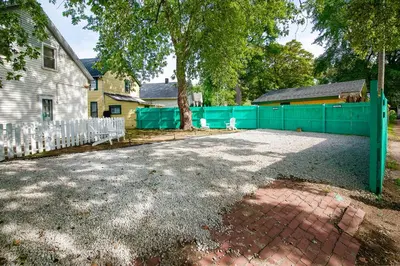 a yard with a fence and a tree and a house at The Tremont Emerald - By Christmas Story House - Historic Charm & Modern Comfort Near Downtown With Parking, 300MB Wifi & Self Check-In in Cleveland