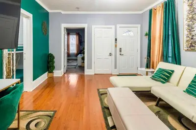 a living room with a white couch and green walls at The Tremont Emerald - By Christmas Story House - Historic Charm & Modern Comfort Near Downtown With Parking, 300MB Wifi & Self Check-In in Cleveland