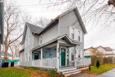 a gray house with a green door on a street at The Tremont Emerald - By Christmas Story House - Historic Charm & Modern Comfort Near Downtown With Parking, 300MB Wifi & Self Check-In in Cleveland