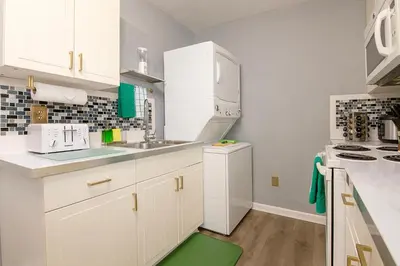 a kitchen with white cabinets and a green rug at The Tremont Emerald - By Christmas Story House - Historic Charm & Modern Comfort Near Downtown With Parking, 300MB Wifi & Self Check-In in Cleveland