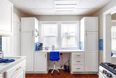a kitchen with white cabinets and a desk with a blue chair at The Sapphire Haven - Your Old Brooklyn Oasis Awaits Families, Couples, Business Travelers Near Downtown With Parking, 300 MB WiFi & Self Check-In in Cleveland