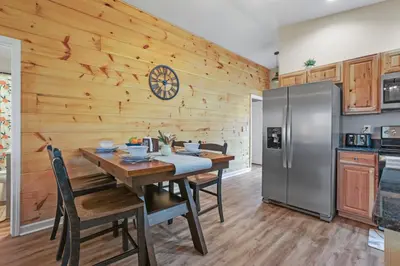 a kitchen with a table and a stainless steel refrigerator at Cabin with King Bed , XBOX, HotTub, Games, Firepit , Stargazing Dome in Logan