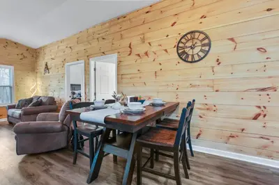 a dining room with a table and a clock on the wall at Cabin with King Bed , XBOX, HotTub, Games, Firepit , Stargazing Dome in Logan