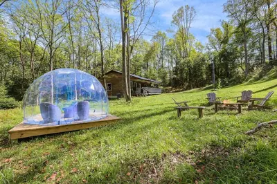a glass dome on a wooden table in a field at Cabin with King Bed , XBOX, HotTub, Games, Firepit , Stargazing Dome in Logan