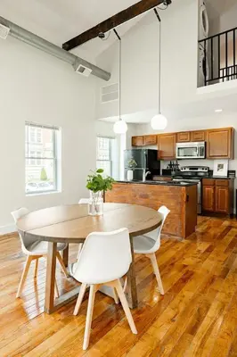 a kitchen with a wooden table and white chairs at Soaring 2BR Parkside Loft Walkable to it All in Cincinnati