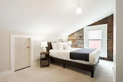 a bedroom with a bed and a brick wall at Soaring 2BR Parkside Loft Walkable to it All in Cincinnati