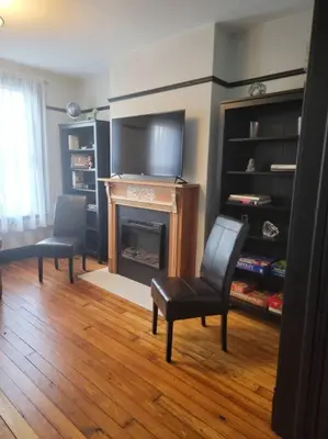 a living room with a fireplace and a tv at 1895 meets 2023 Townhouse. in Hamilton