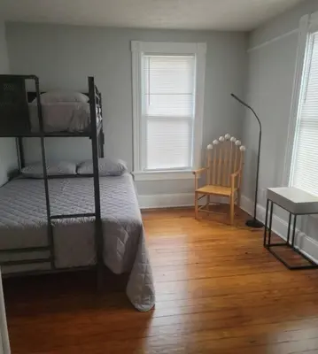 a bedroom with two bunk beds and a chair at 1895 meets 2023 Townhouse. in Hamilton