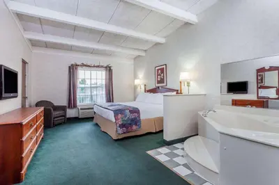 a hotel room with a bed and a sink at Days Inn & Suites by Wyndham Lexington in Lexington
