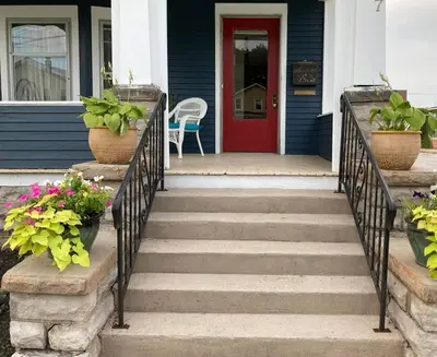 a blue house with a red door and stairs with flowers at Fiesinger House - Private 3-bd Unit in Historic Home, Downtown Sandusky in Sandusky