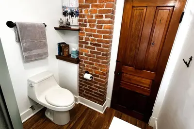 a bathroom with a toilet and a brick wall at Fiesinger House - Private 3-bd Unit in Historic Home, Downtown Sandusky in Sandusky