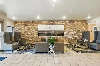 a lobby with chairs and a stone wall at Cobblestone Hotel & Suites - Russells Point at Indian Lake in Russells Point
